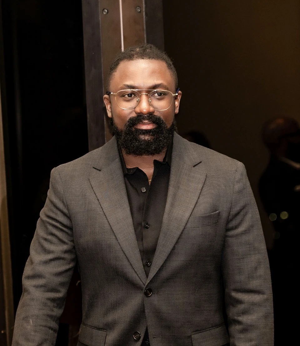 Chinedum Ucheoma wearing a charcoal suit and glasses